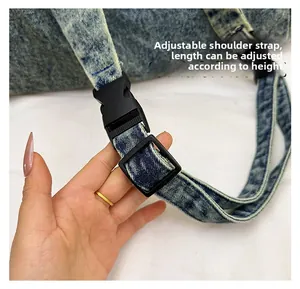 Close-up of adjustable shoulder strap with black plastic buckle on denim handbag