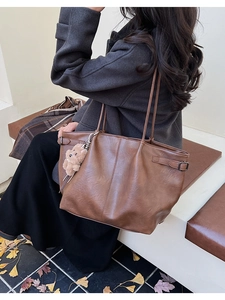 Detail of dark brown faux suede tote bag featuring a plush bear charm and buckle