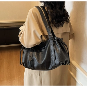 Détail du sac à main noir à motif litchi avec œillets métalliques et cordon de serrage latéral