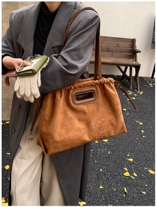 Détail d'un sac cabas en daim marron avec cordon de serrage et breloque coeur en métal
