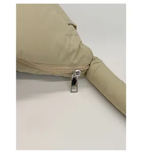 Detail of silver metal zipper on beige quilted padded handbag with smooth closure