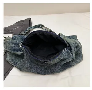 Macro shot showing the spacious interior and zipper closure of the denim tote bag