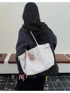 Detail of large cream white faux leather tote bag with a cute brown plush bear charm