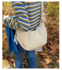 Outdoor model wearing a creamy white quilted puffer bag with knotted wide strap details