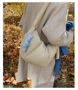 Borsa a tracolla imbottita bianco crema con fiocco blu indossata con cappotto autunnale