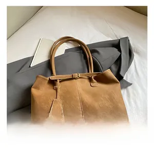 Détail du grand sac cabas camel avec boucle dorée et longues anses sur lit blanc
