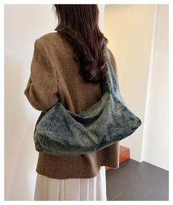 Detail of a large denim hobo shoulder bag showing washed blue fabric and soft texture