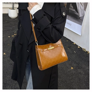 Chic quilted tan underarm bag with gold rotating lock worn by a model in black coat