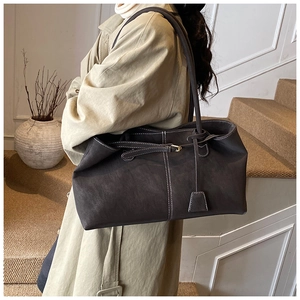 Détail d'un grand sac cabas marron foncé avec surpiqûres blanches porté par un mannequin