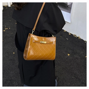 Detail of brown quilted leather shoulder bag with gold metal buckle and adjustable strap