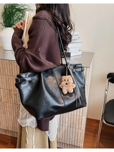 Macro detail of large black suede tote bag with textured surface and cute bear charm