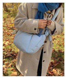 Close-up of light blue quilted puffer crossbody bag with soft padded texture and strap