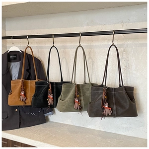 Detail of four large tote bags in varied colors with contrast stitching and bear charm