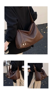 Détail du sac à bandoulière tressé marron foncé avec texture fine et glands dorés