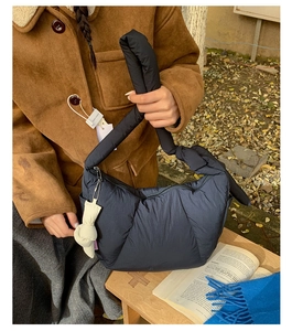 Vista laterale di una borsa trapuntata nera con manico annodato e ciondolo di peluche