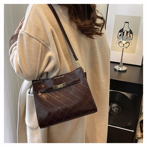 Detail of a dark brown quilted crossbody bag with gold metal twist-lock and shoulder strap