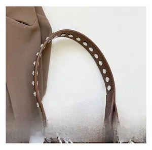 Detail des braunen Lederriemens mit silbernen Metallnieten und stabilen Verschlüssen