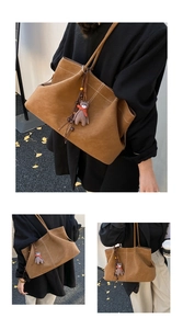 Detail of brown faux suede tote bag featuring white contrast stitching and a plush bear charm