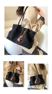 Detail of black suede tote bag featuring white contrast stitching and a plush bear charm