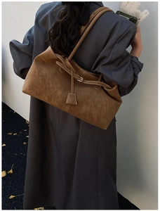 Detail of a large brown suede tote bag styled with a grey coat for fall fashion