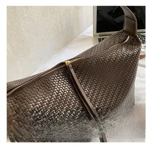 Détail du sac hobo tressé marron foncé avec fermeture éclair dorée et tirette en cuir