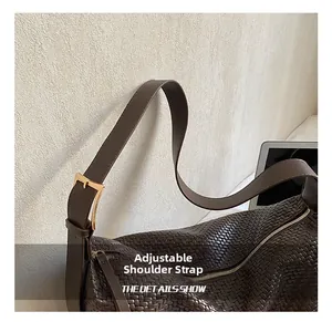 Détail de la bandoulière réglable et boucle dorée sur un sac tissé marron foncé