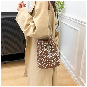 Détail des rivets argentés sur le sac seau en cuir marron avec bandoulière chaîne