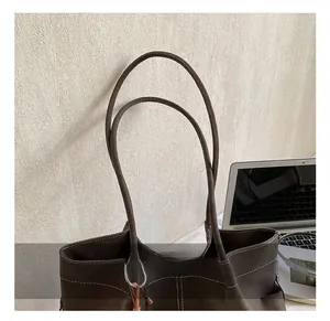 Detail of soft suede tote bag featuring white contrast stitching and durable long handles