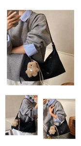 Close-up of black hobo shoulder bag texture with cute brown plush bear accessory