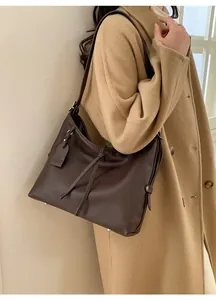 Gros plan sur la texture en cuir marron foncé et le cordon décoratif de ce grand sac