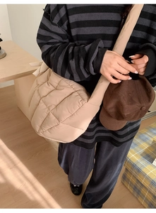 Détail d'un sac hobo matelassé beige clair avec texture moelleuse et forme de croissant épurée