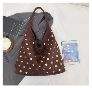 Detail of dark brown suede tote bag with gold rivets and daily essentials for work