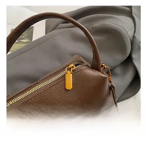 Détails de la fermeture éclair dorée et du cuir marron à grain de litchi sur le mini sac