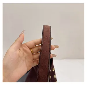 Detail of dark brown matte suede handle with sturdy stitching and gold rivet accents