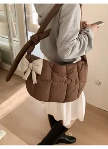 Détail du sac matelassé marron foncé avec grand nœud crème et bandoulière souple