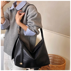 Détail de la texture en cuir tressé noir d'un grand sac à bandoulière hobo