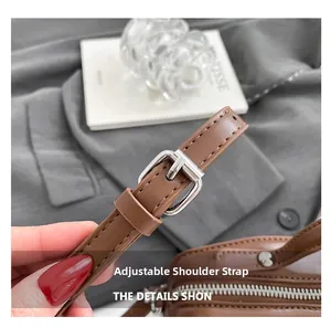 Detail of adjustable brown leather shoulder strap with a silver metal buckle on bag