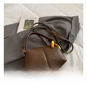 Détail du sac en cuir marron vintage avec poignée en métal doré et texture de grain