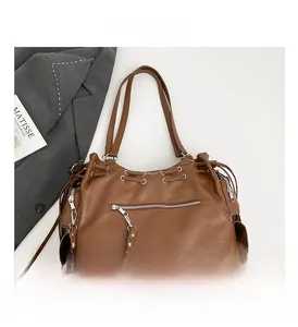 Detail view of large dark brown tote bag with metallic zippers and drawstring accents