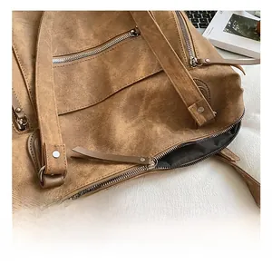 Détail du sac vintage en daim marron avec fermetures éclair argentées et rivets renforcés