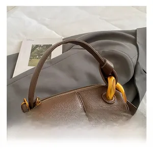 Détails d'un sac à main en cuir marron foncé avec chaîne dorée et poignée confortable