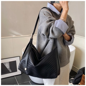 Détail d'un sac à bandoulière tressé noir avec large sangle et grande capacité interne
