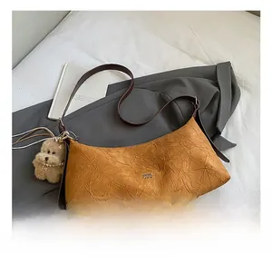 Macro detail of caramel brown textured leather bag with teddy bear charm and logo