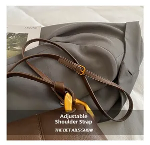 Détail de la bandoulière réglable en cuir avec boucle en métal doré sur sac marron