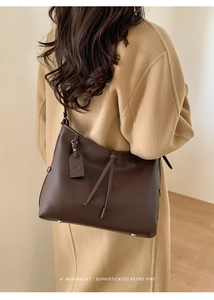 Sac fourre-tout en cuir marron café porté avec un manteau camel dans un style rétro chic