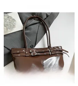 Detail of dark brown patent leather shoulder bag with silver eyelet straps and buckle