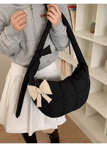 Détail du sac matelassé noir avec accessoire de nœud beige et bandoulière à nœud décoratif