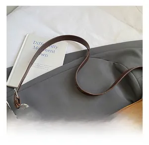 Detail of caramel pleated leather shoulder bag with silver metal ring and slim strap