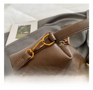Gros plan sur les attaches dorées et la bandoulière d'un sac à main marron grainé