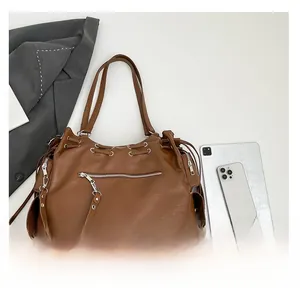 Detail view of large brown faux leather tote bag with front zipper and drawstring accents